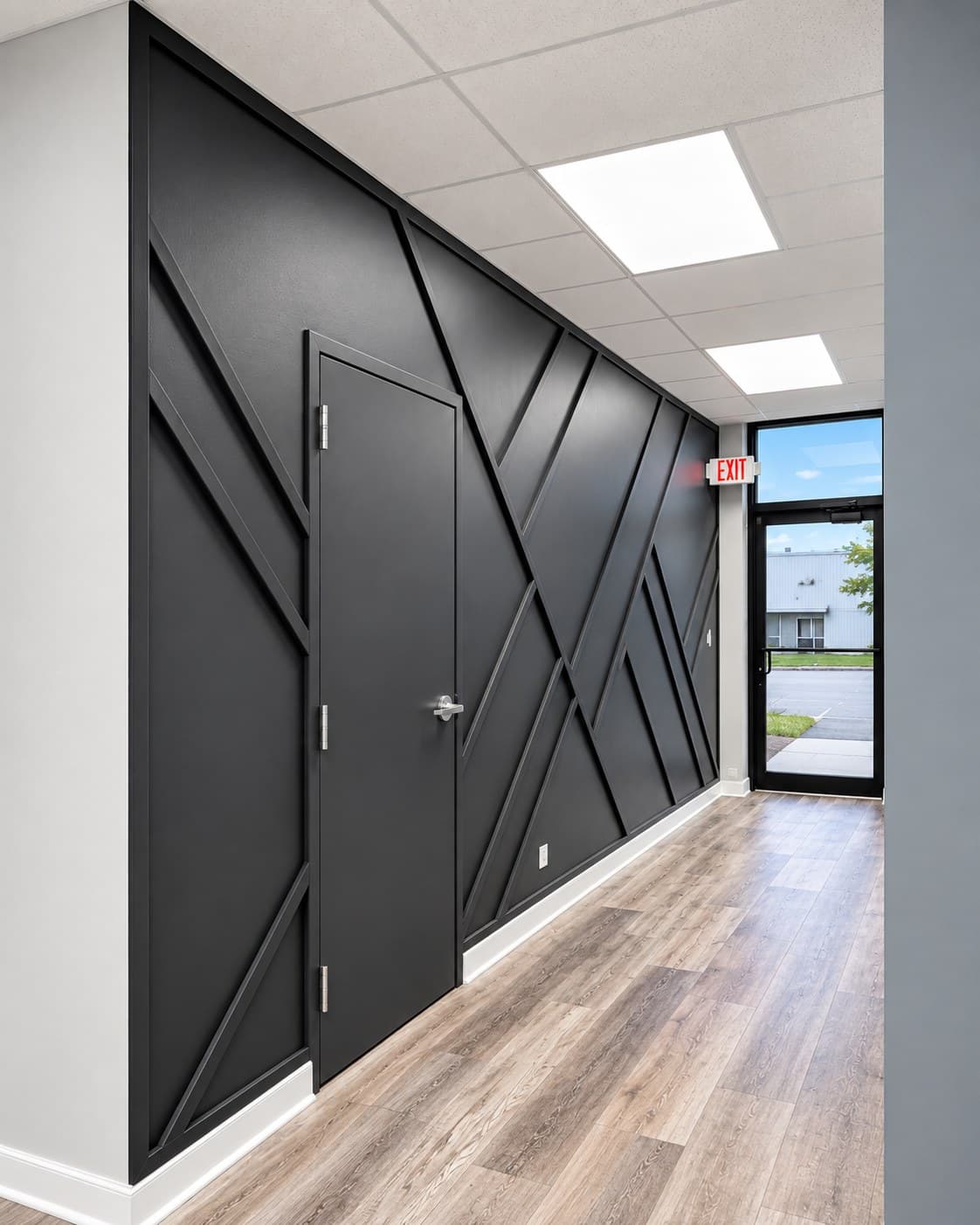 Wide hallway view of a black geometric accent wall leading to a glass exit door