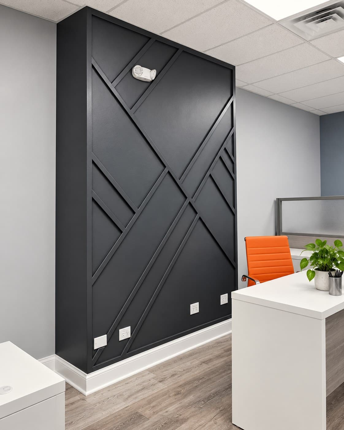 Black geometric accent wall wrapping a corner into a private office with an orange chair and white desk