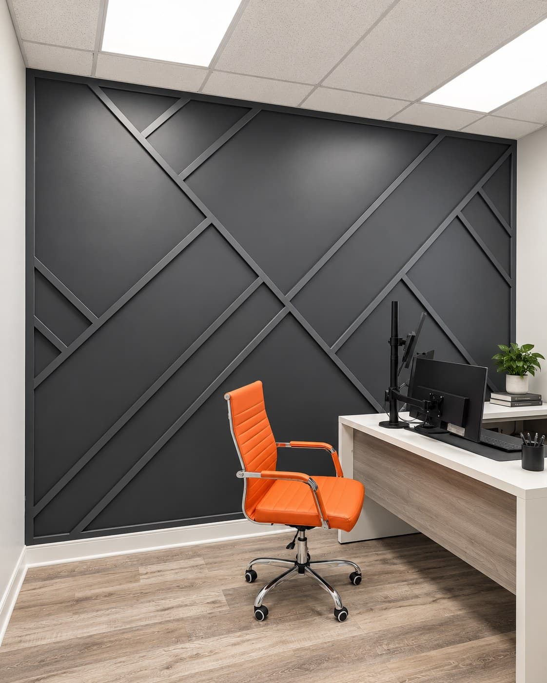 Private office with a black geometric accent wall, orange office chair, and dual-monitor desk setup