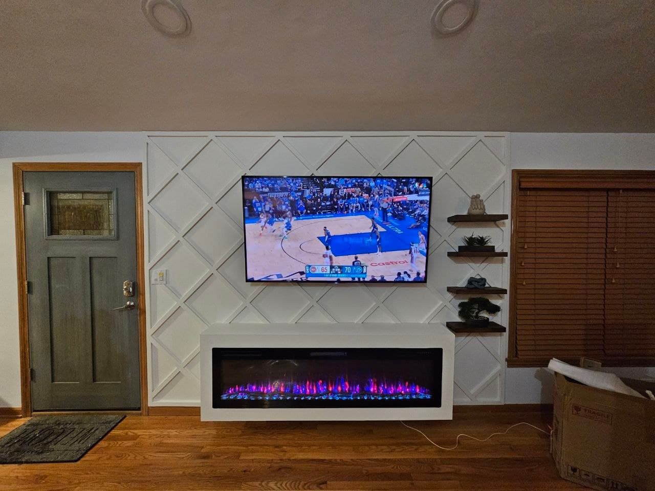 White diamond lattice accent wall with floating shelves and a fireplace TV stand