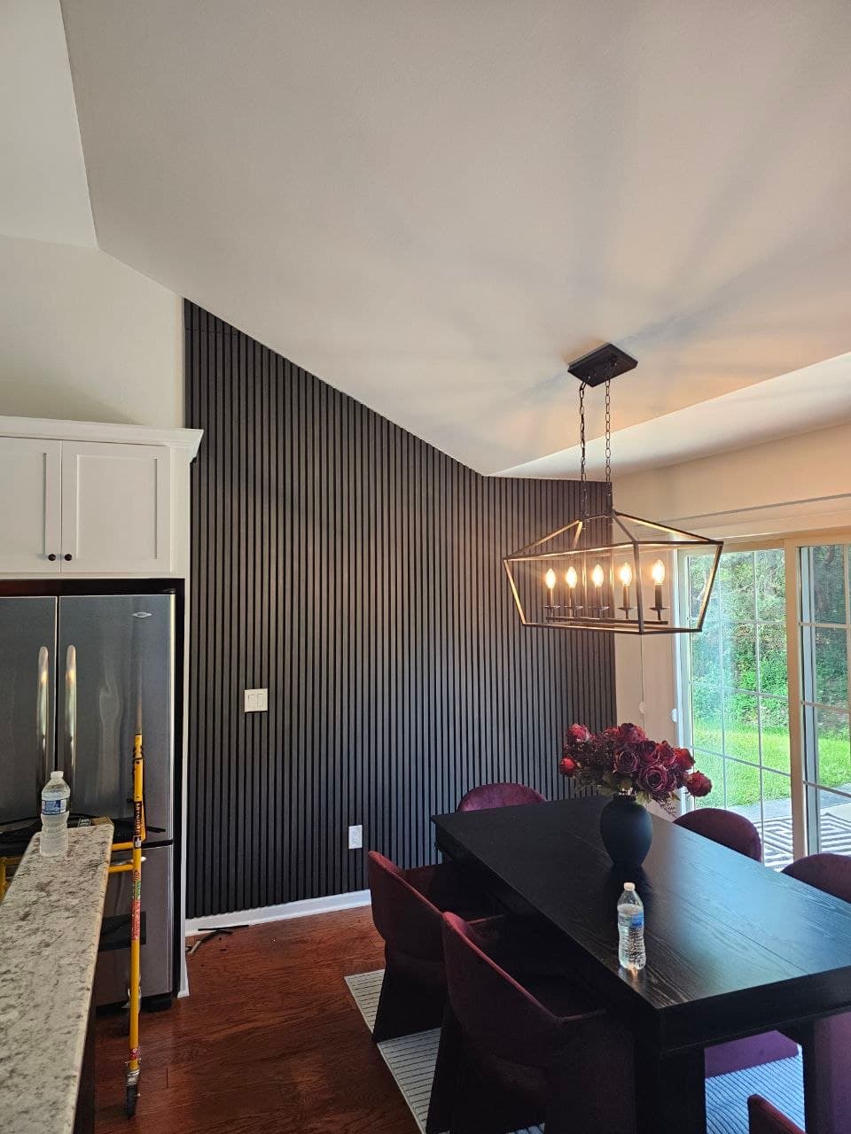 Black wood slat accent wall in a dining room with vaulted ceiling