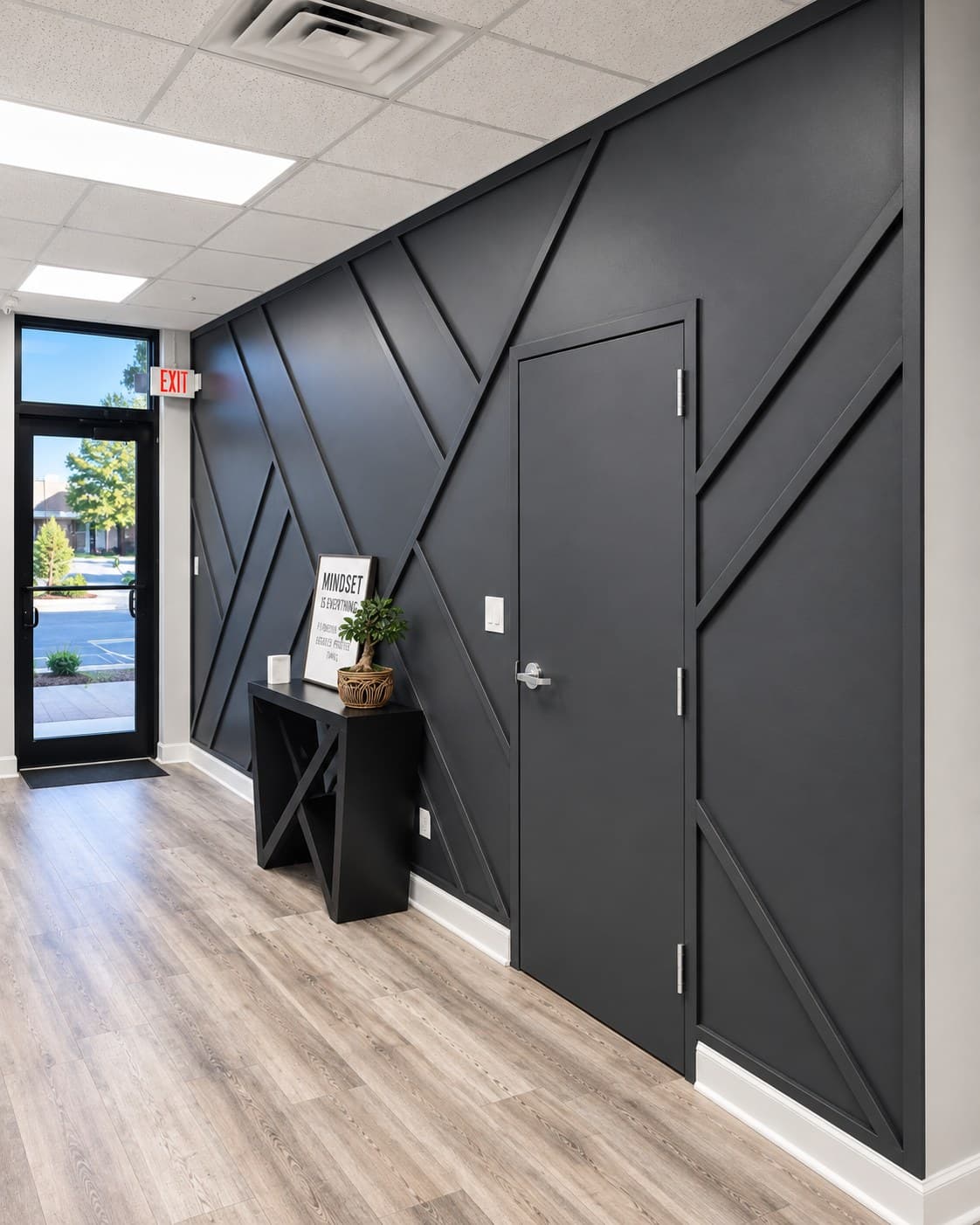 Black geometric accent wall in an office hallway, with a console table and framed print near the entrance